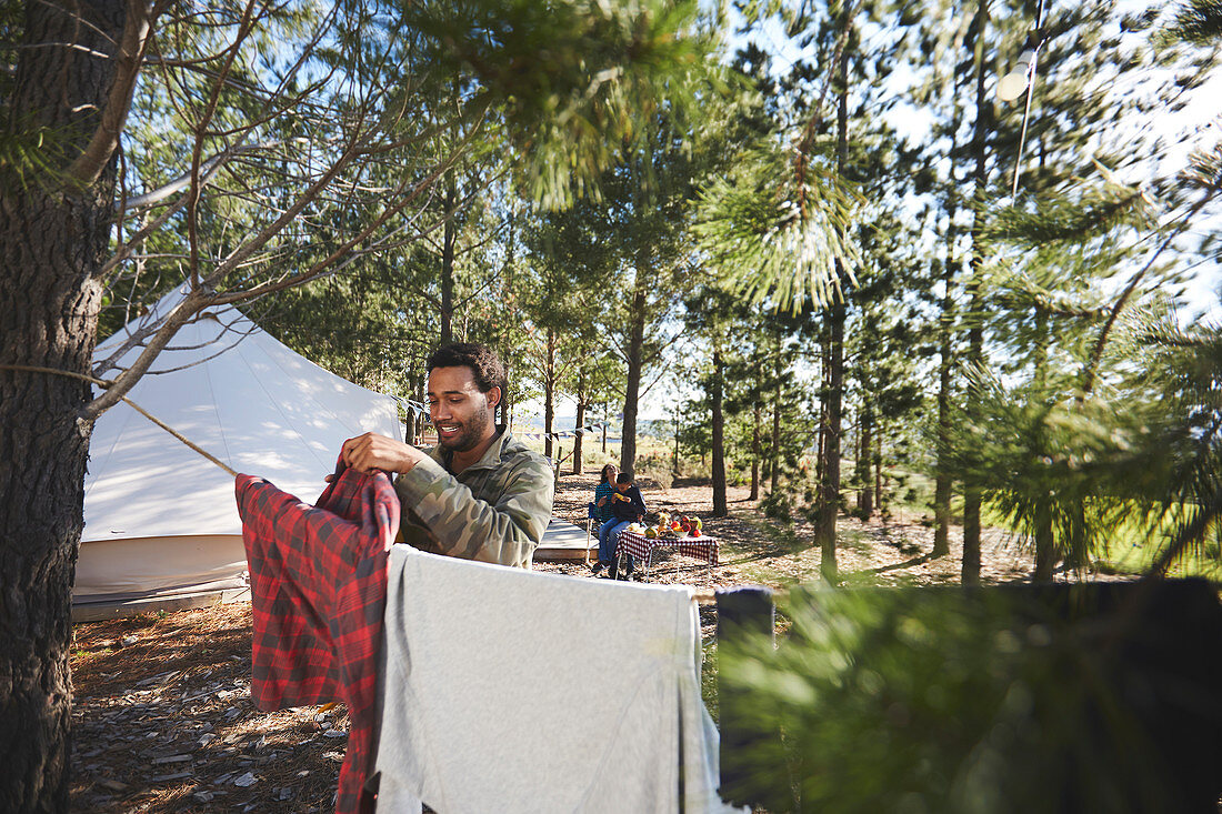 Man hanging laundry on clothesline at campsite in woods
