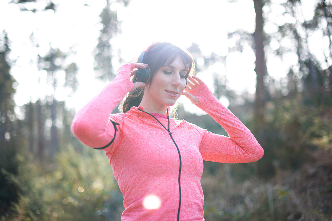 Female runner with headphones in woods