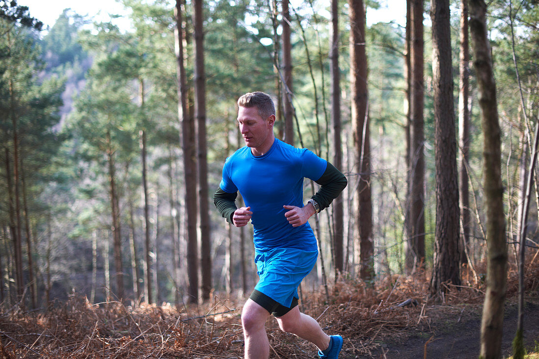 Man running on trail in sunny autumn woods