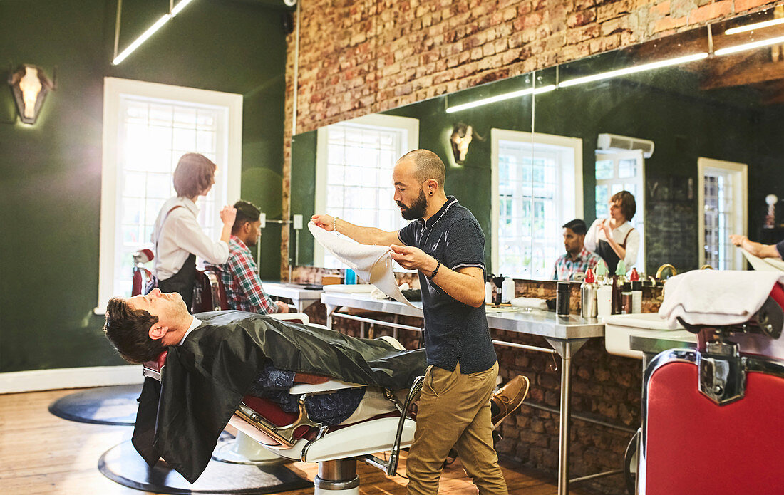 Male barber preparing to steam face of customer