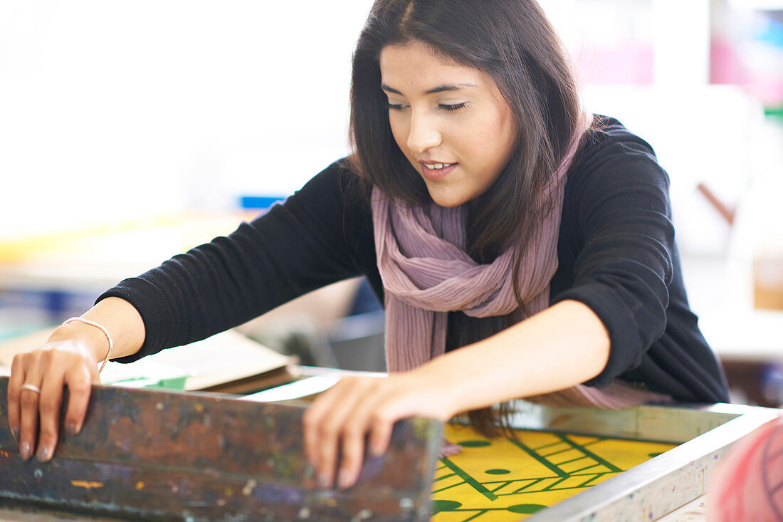 Female artist screen printing in art studio