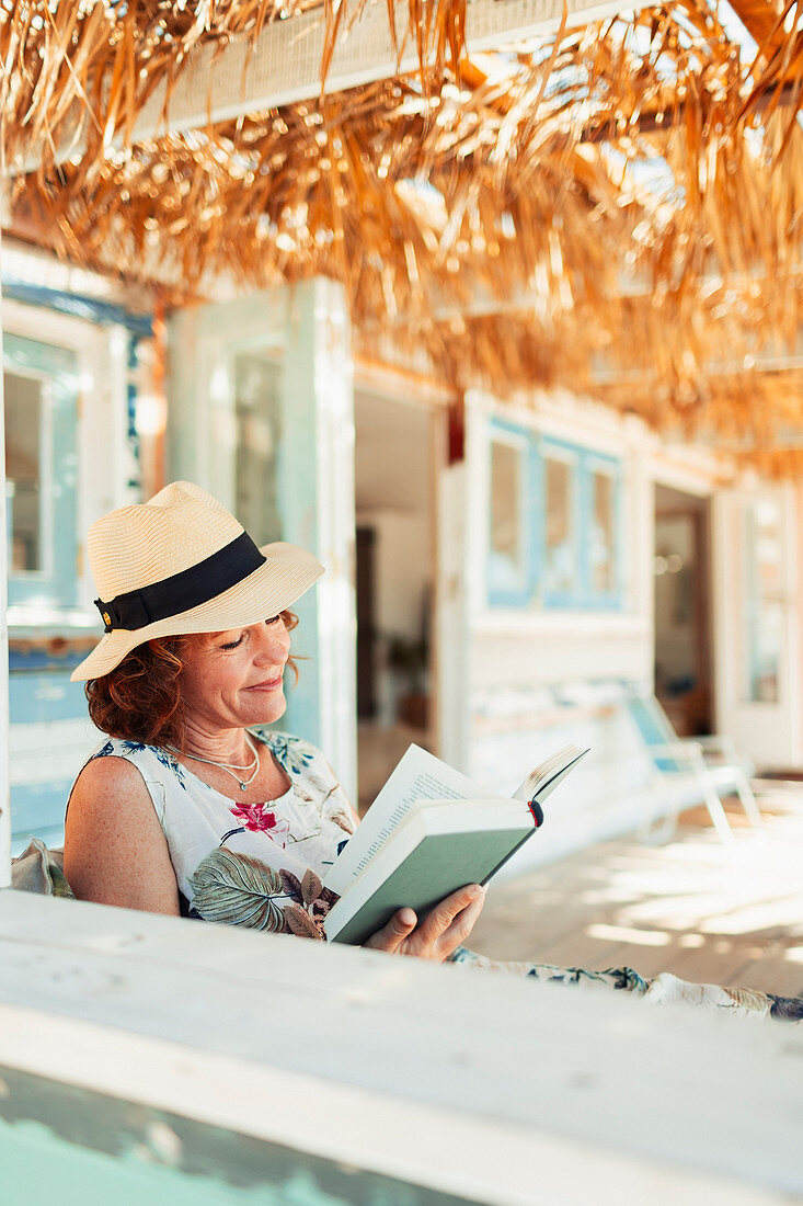 Woman reading book on beach hut patio