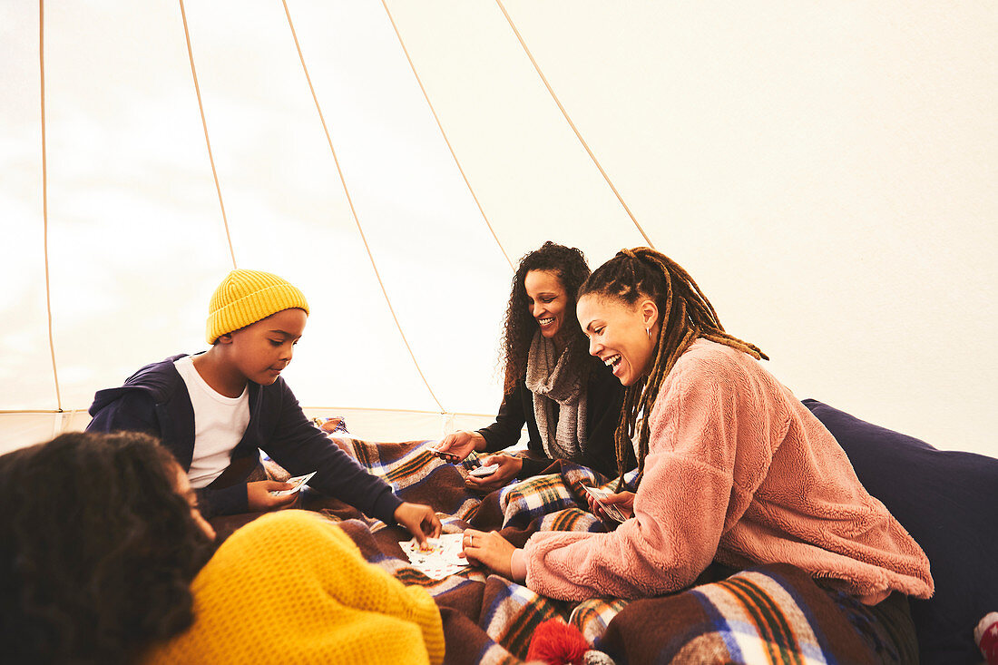 Lesbian couple and kids playing cards in camping yurt