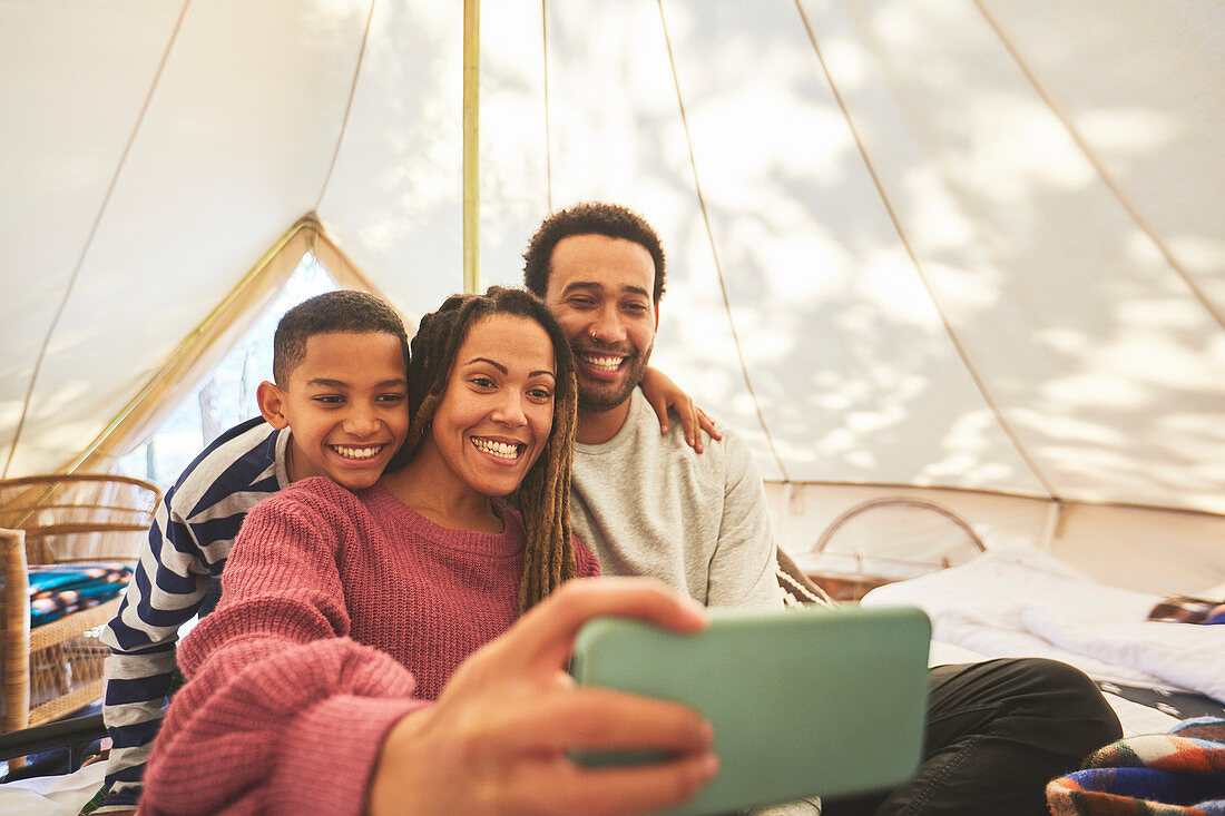 Happy family taking selfie in camping yurt
