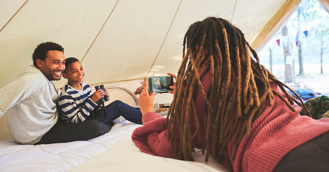 Woman photographing husband and son in camping yurt