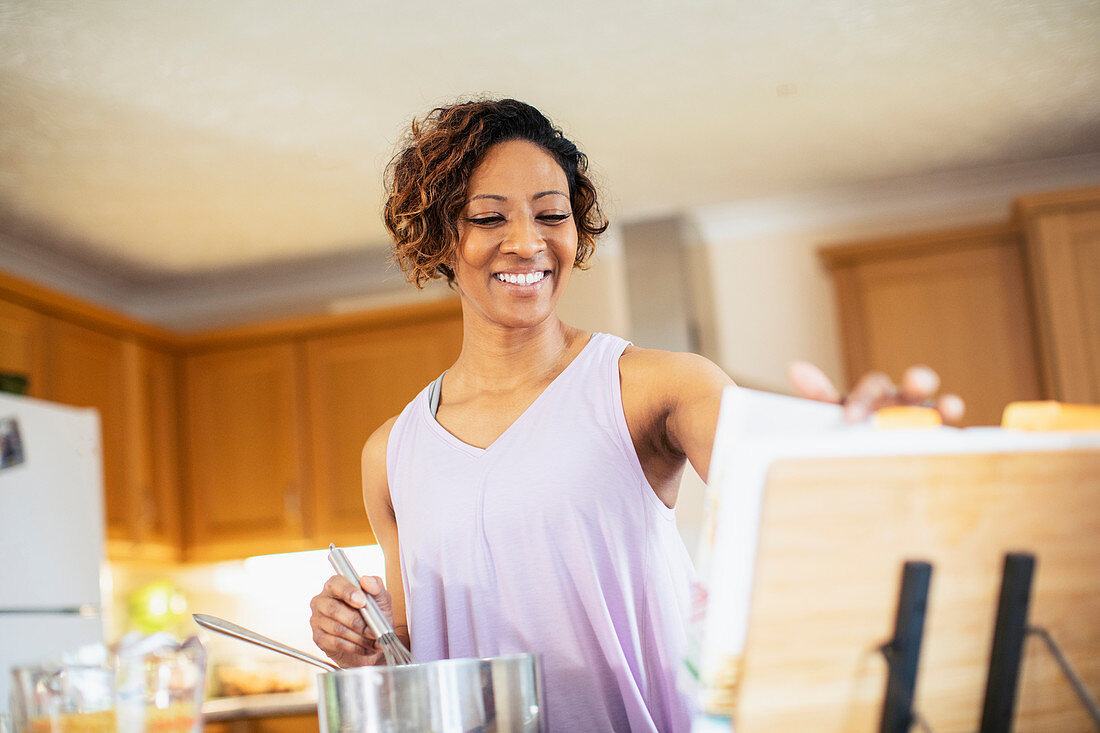 Smiling woman with cookbook cooking