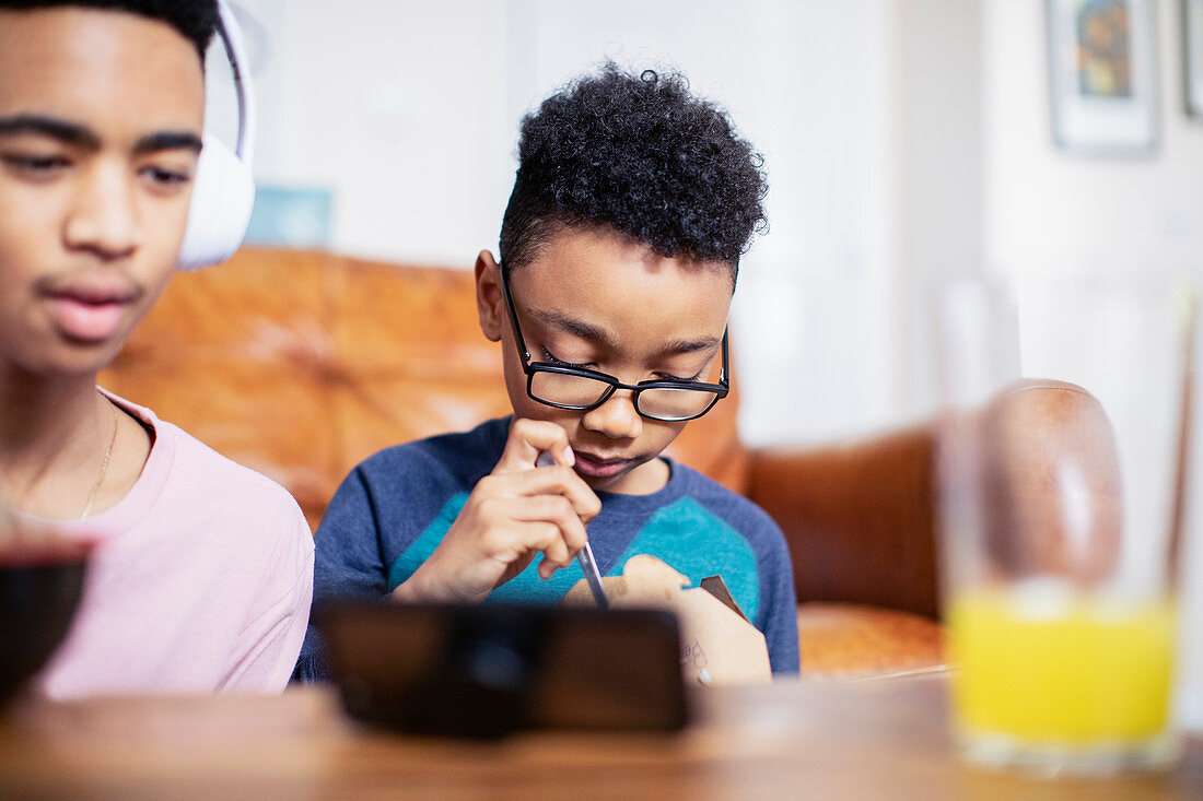 Brothers eating and using smart phone