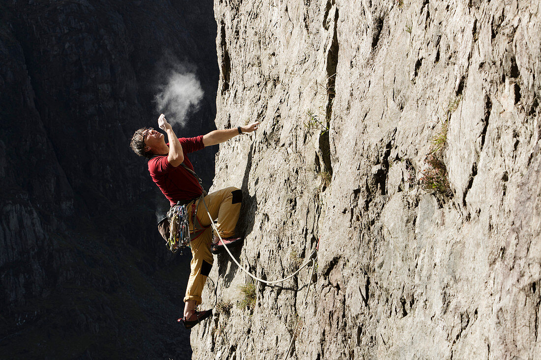 Male rock climber scaling rock face