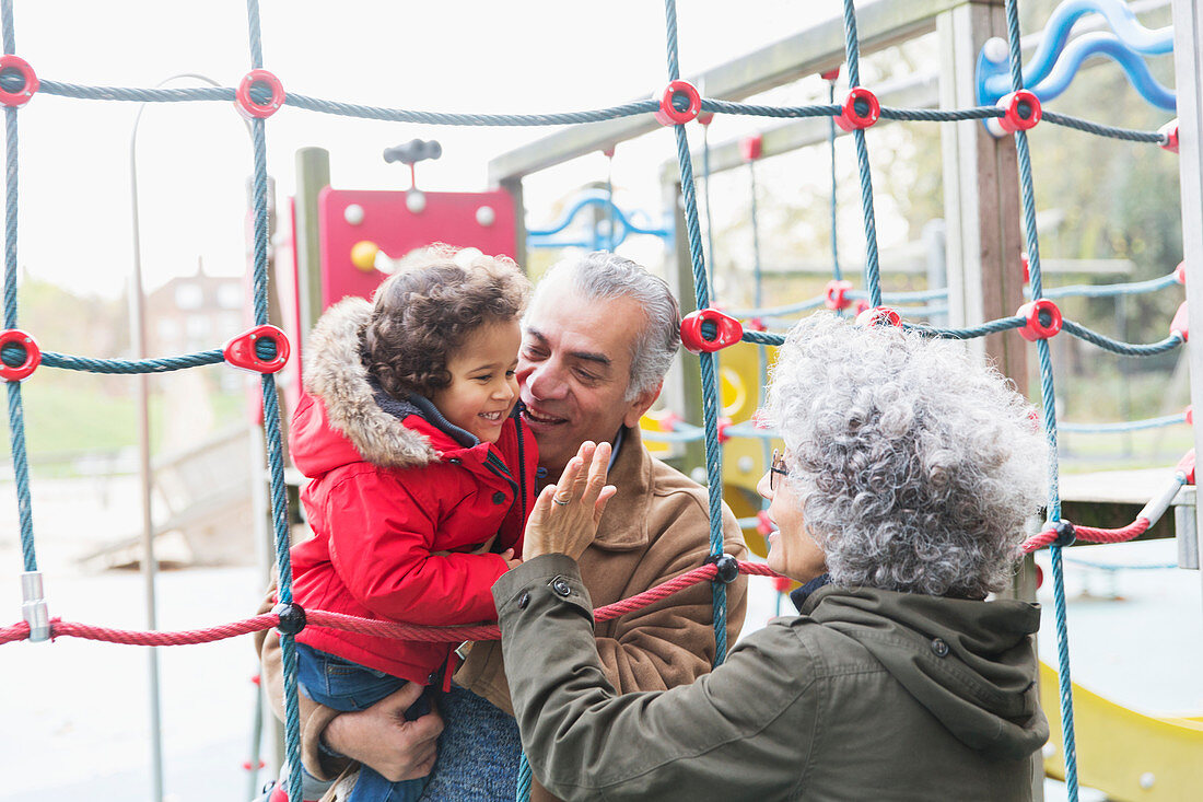 Grandparents playing with grandson at playground
