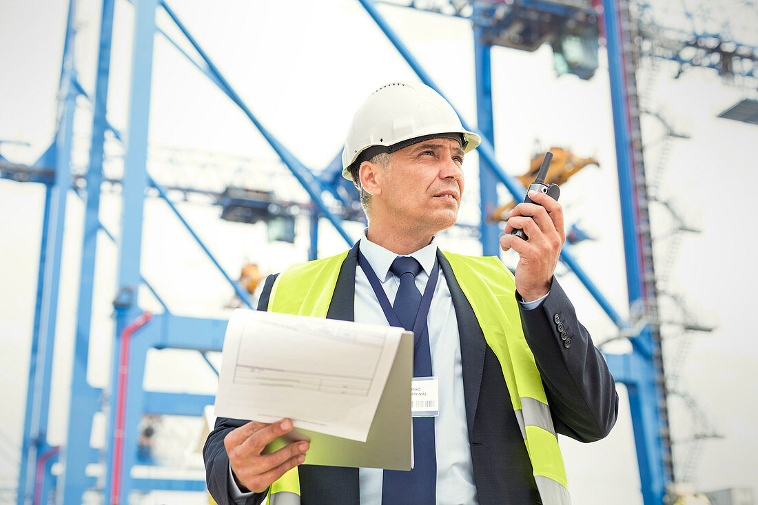 Dock manager with walkie-talkie and clipboard at shipyard