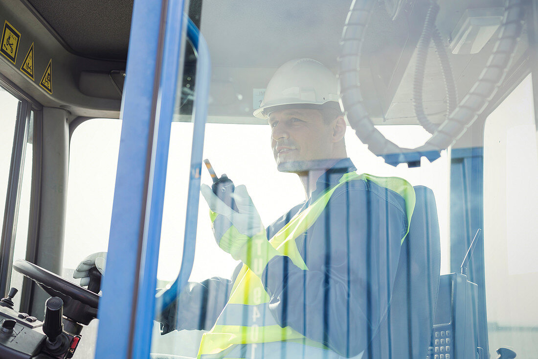 Dock worker with walkie-talkie operating forklift