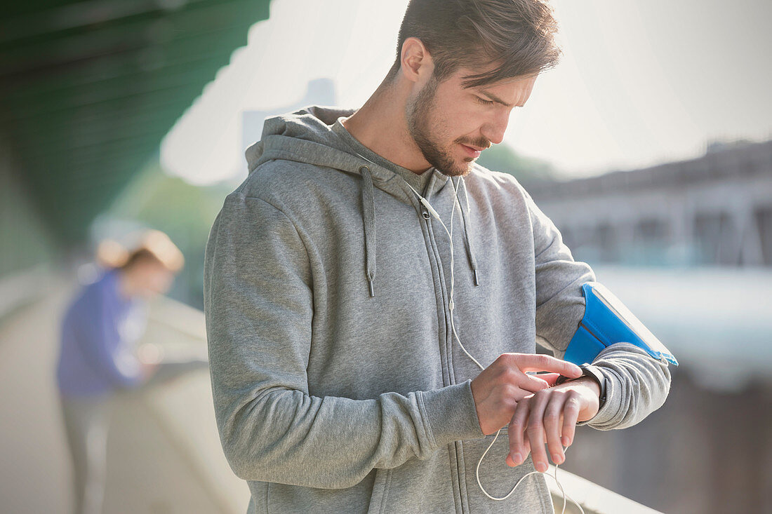 Young male runner checking smart watch