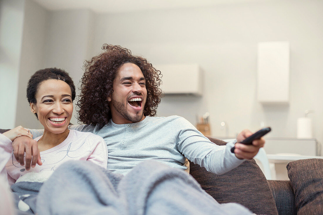 Happy couple relaxing, watching TV on living room sofa