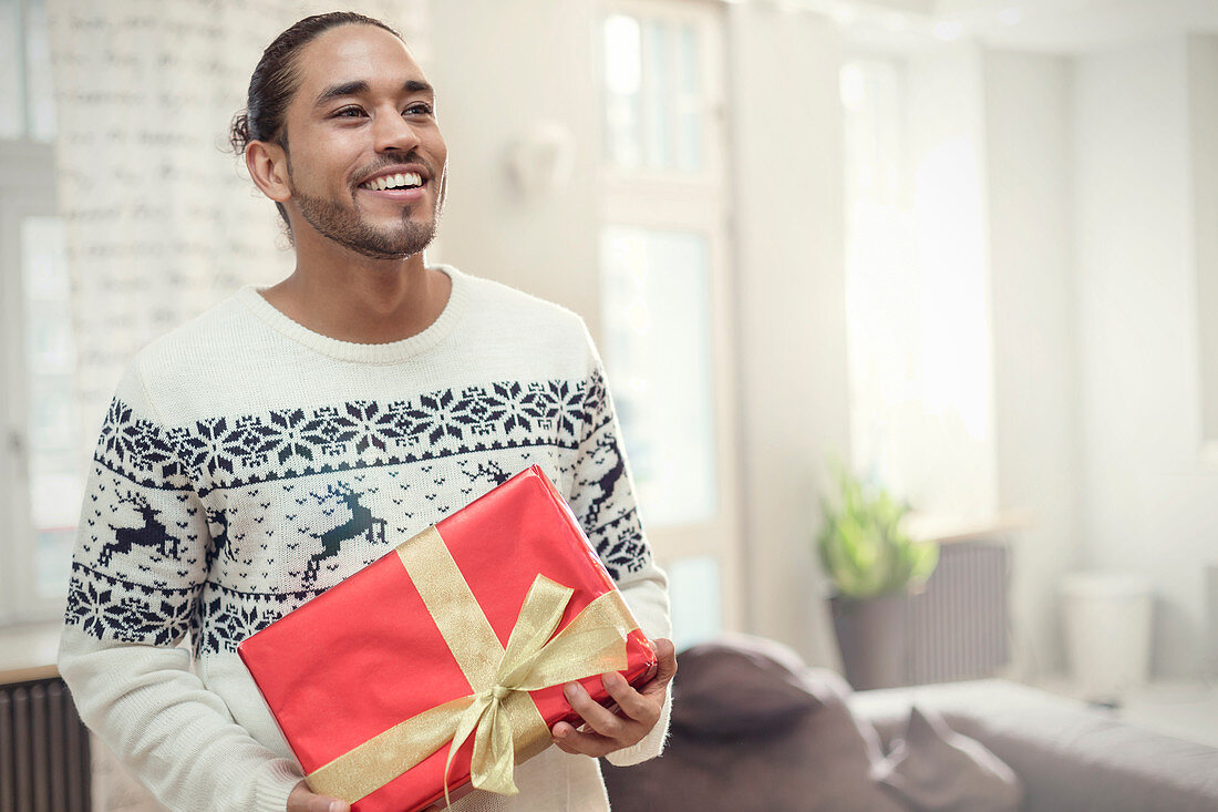 Young man in Christmas sweater holding gift