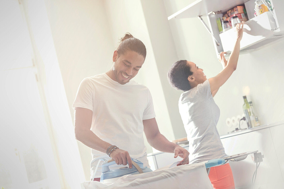 Couple doing laundry, ironing clothes in laundry room