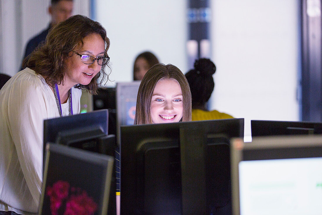 Female teacher helping student at computer in computer lab