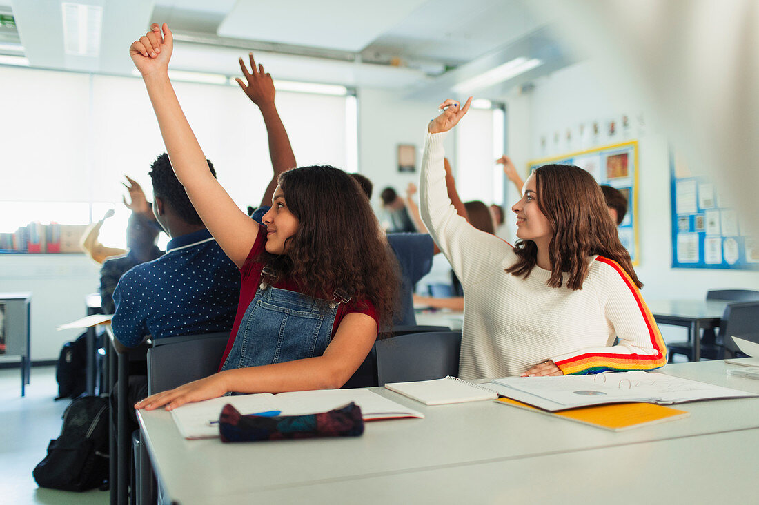 Students with hands raised during lesson in classroom