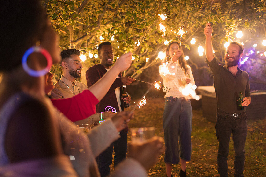 Playful friends with sparklers enjoying garden party