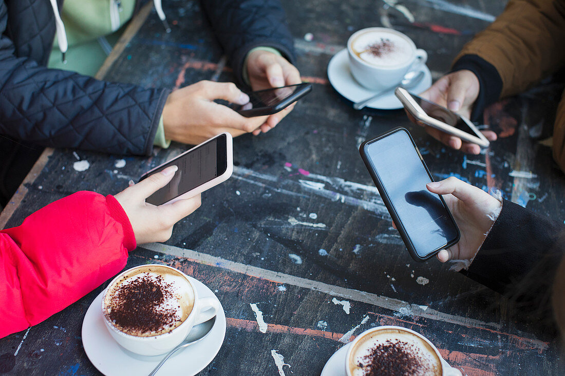 Friends using smart phones and drinking cappuccinos