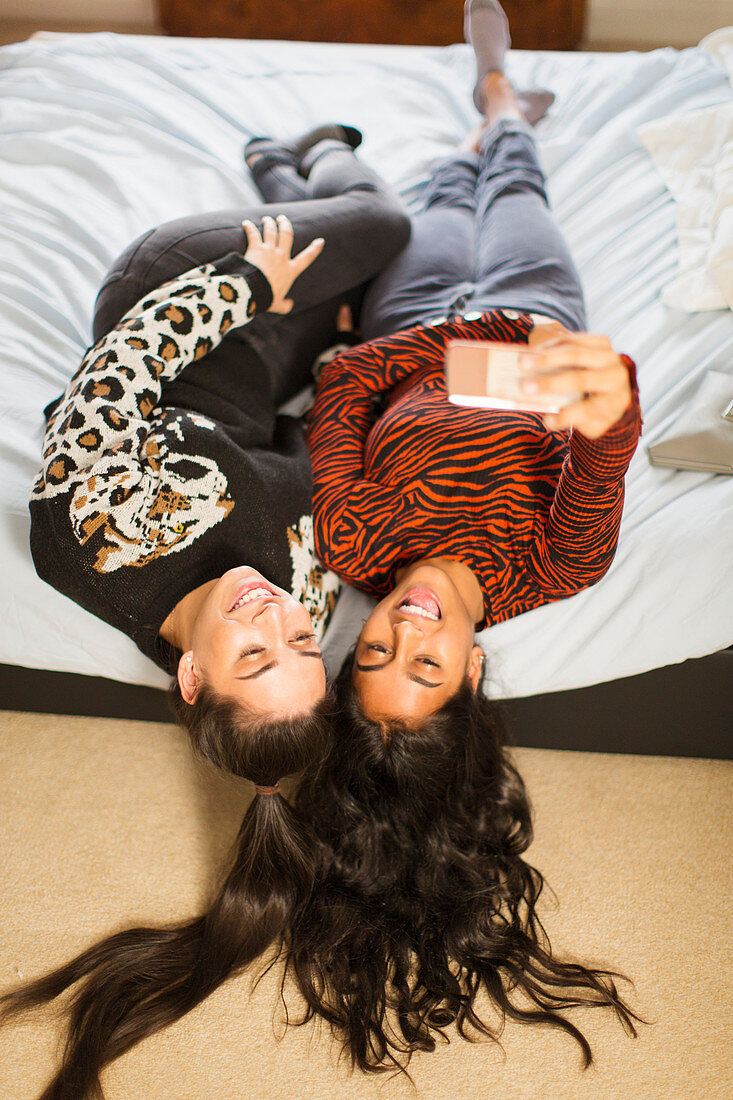 View from above teenage girl friends taking selfie on bed