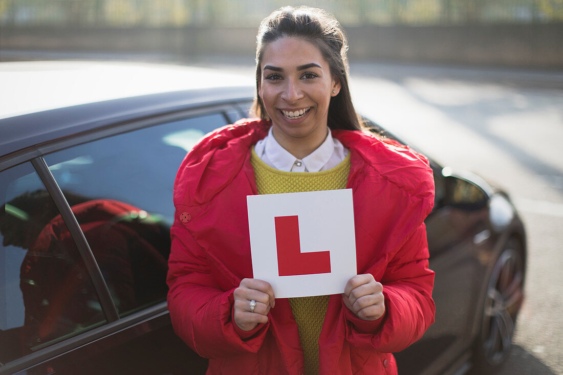 Portrait confident, woman holding learners permit by car