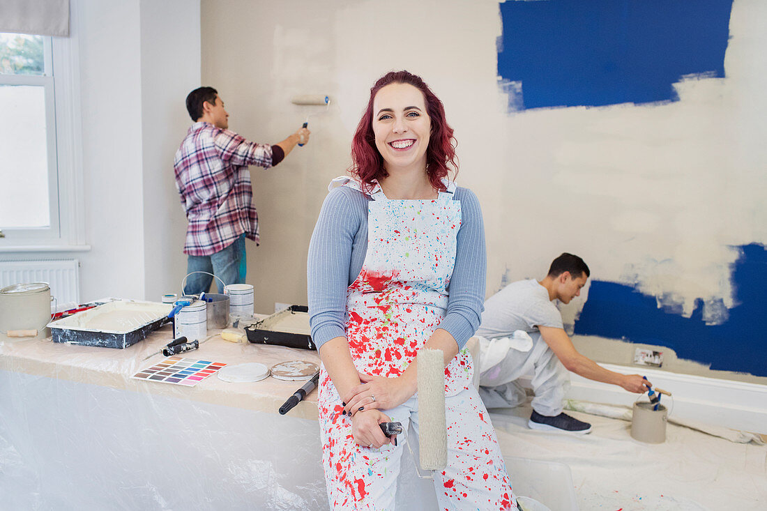 Portrait woman in overalls painting room with friends