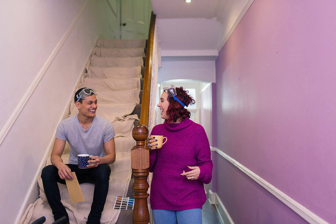 Happy couple redecorating, drinking coffee on stairs