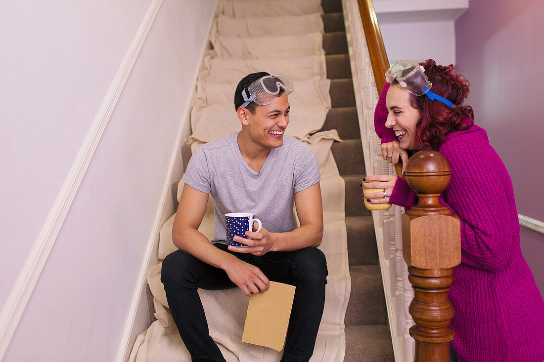 Couple taking coffee break from redecorating on stairs