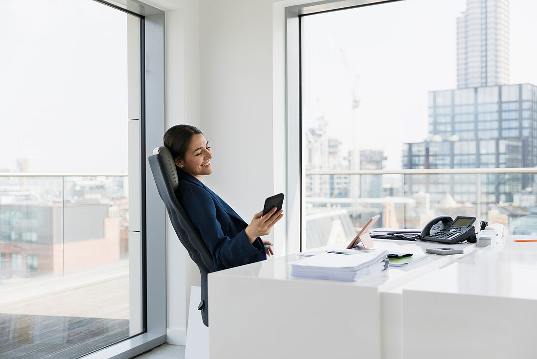 Smiling businesswoman using smart phone in urban office