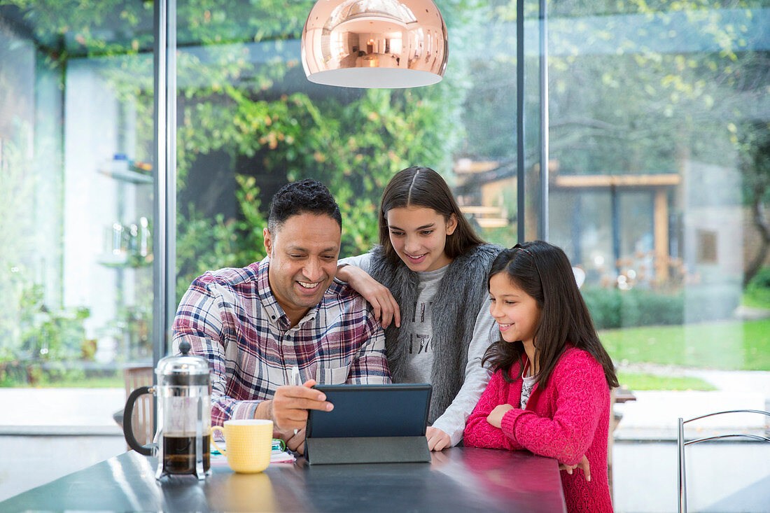 Father and daughters using tablet at breakfast table