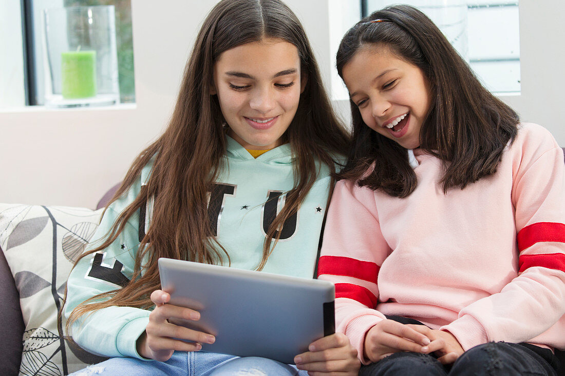 Smiling sisters using digital tablet