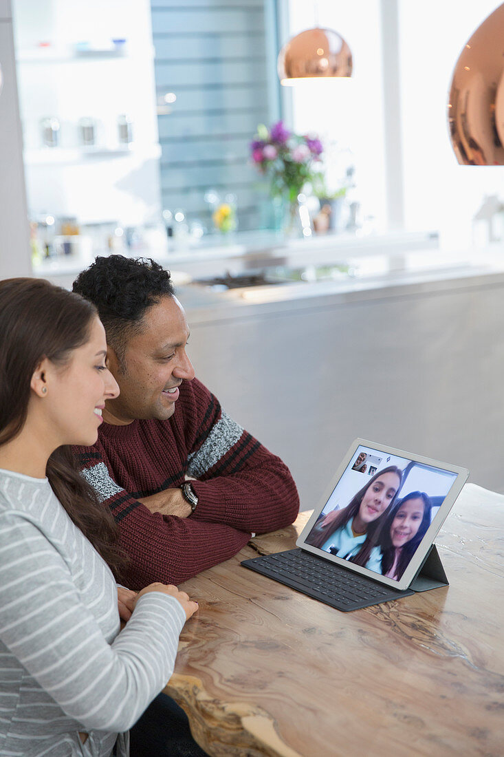 Parents video conferencing with daughters at tablet