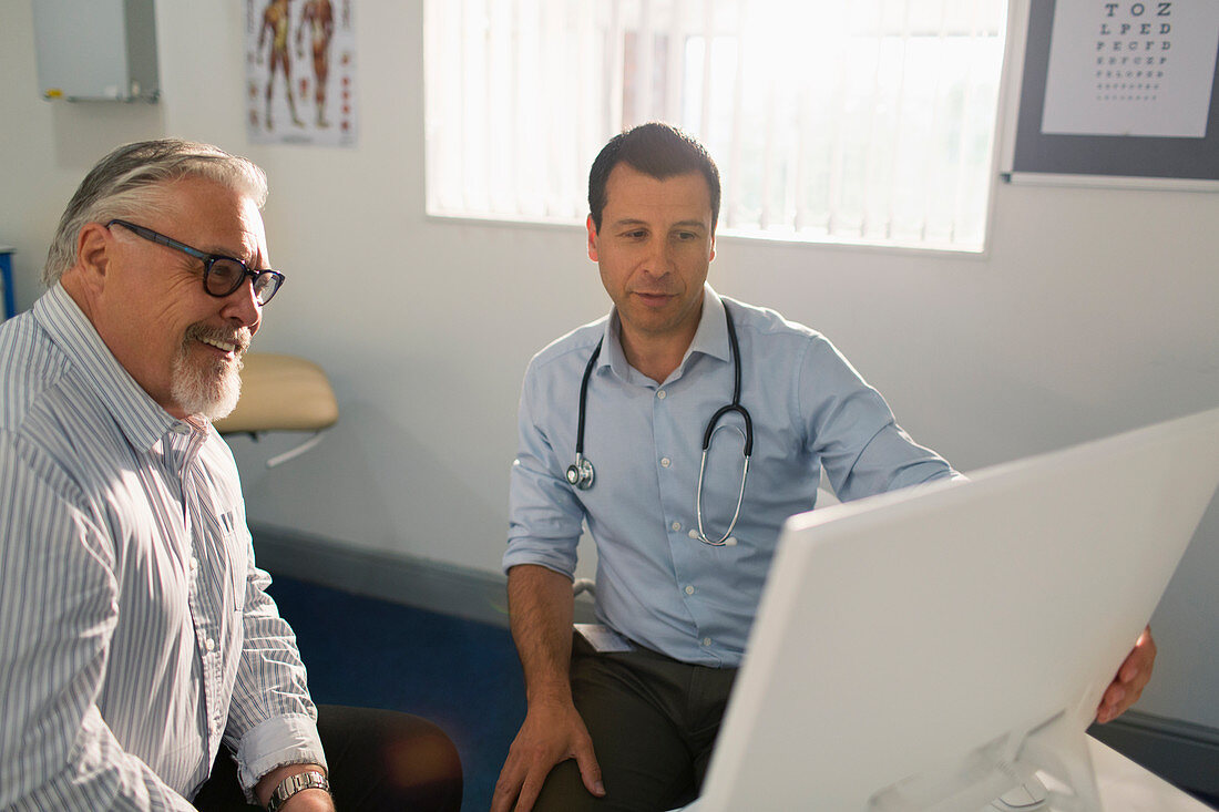 Male doctor meeting with senior patient at computer