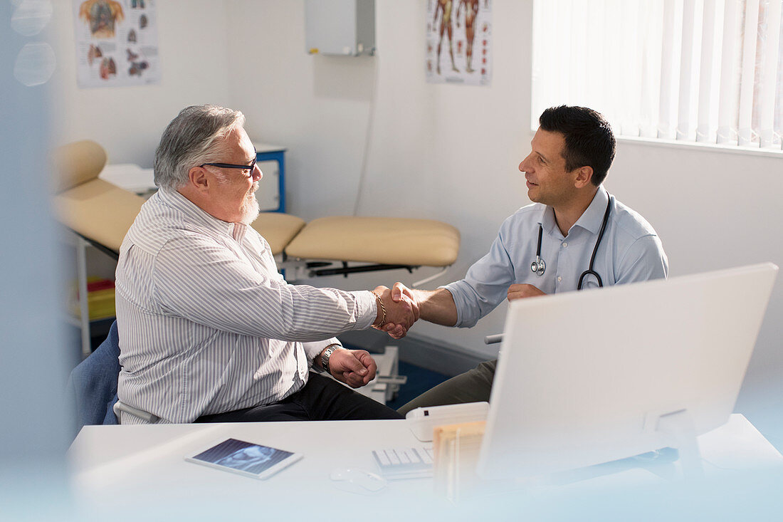 Male doctor shaking hands with senior patient