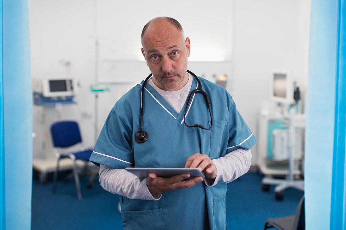 Confident, serious doctor using tablet in hospital room
