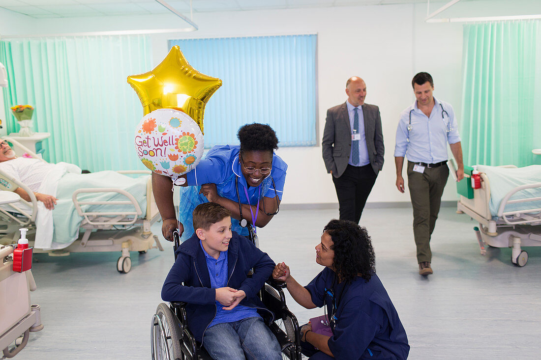 Doctor and nurse talking with boy patient in wheelchair