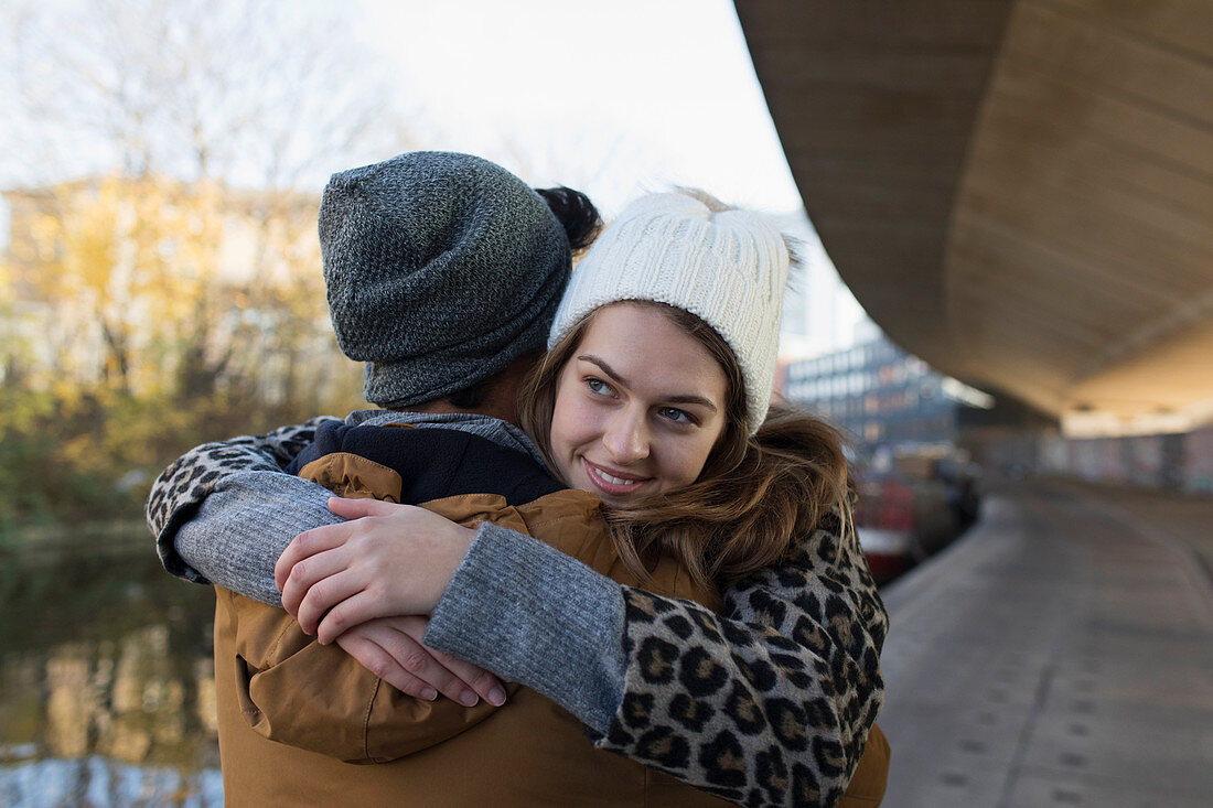 Happy young couple hugging along urban canal