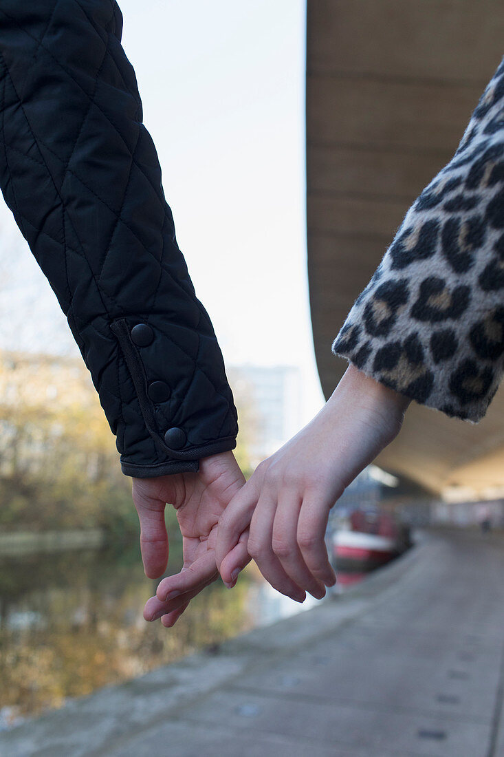 Close up young couple holding hands along canal