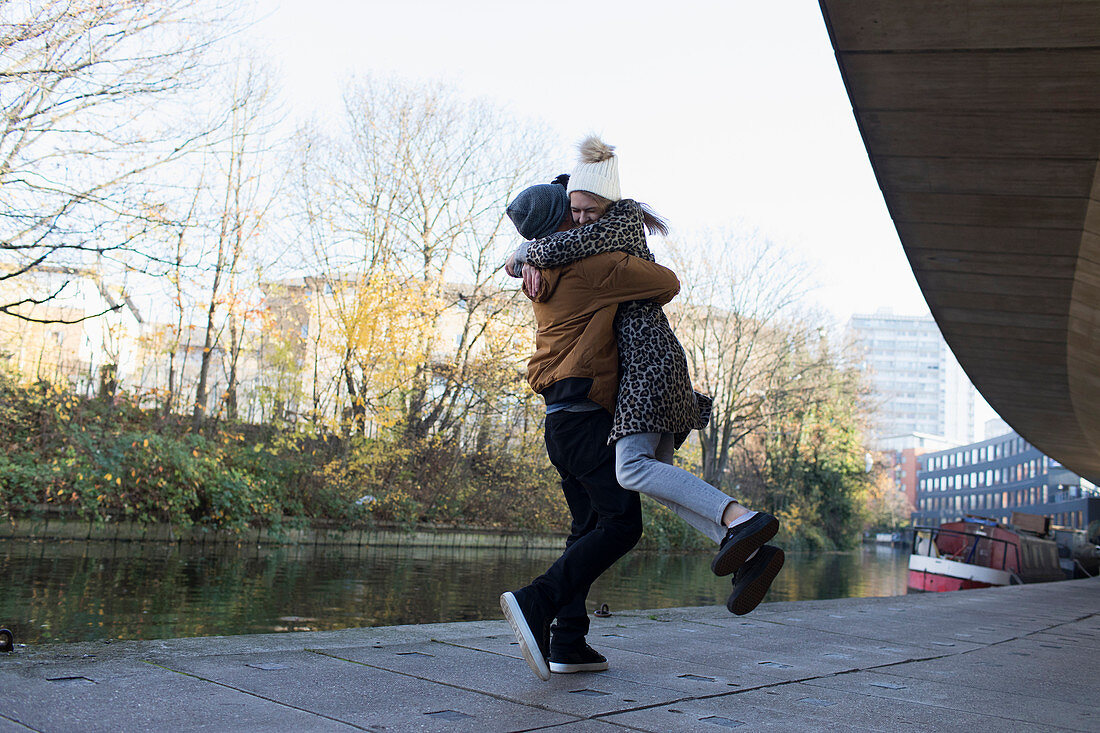 Happy young couple hugging along urban canal