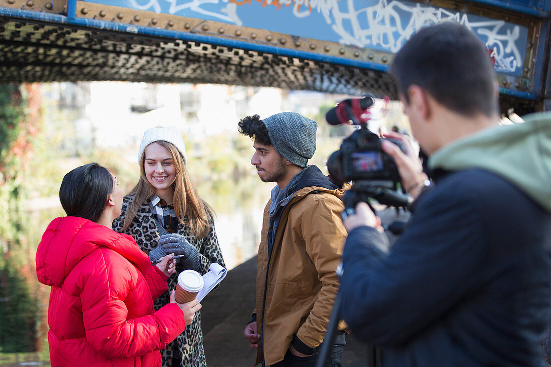Young film students filming under urban bridge