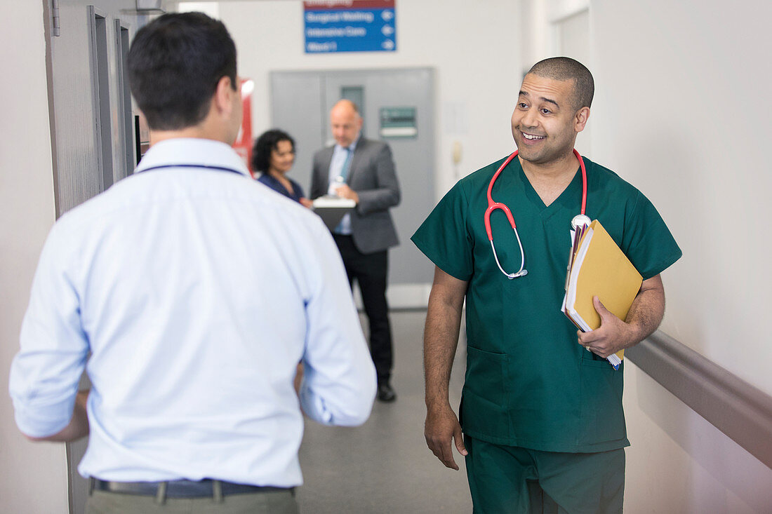 Surgeon greeting passing doctor in hospital corridor