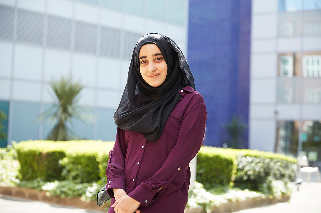 Portrait young woman in hijab outside sunny building