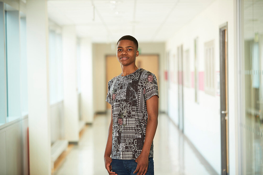 Portrait teenage boy in high school corridor