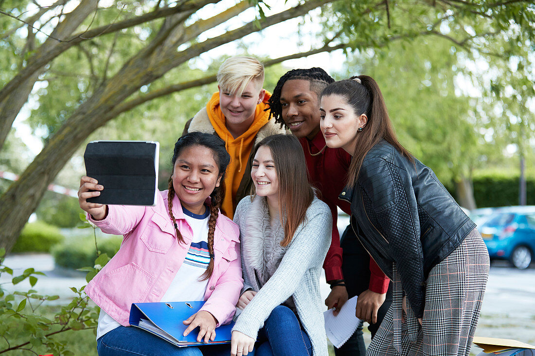 Happy college students taking selfie with digital tablet