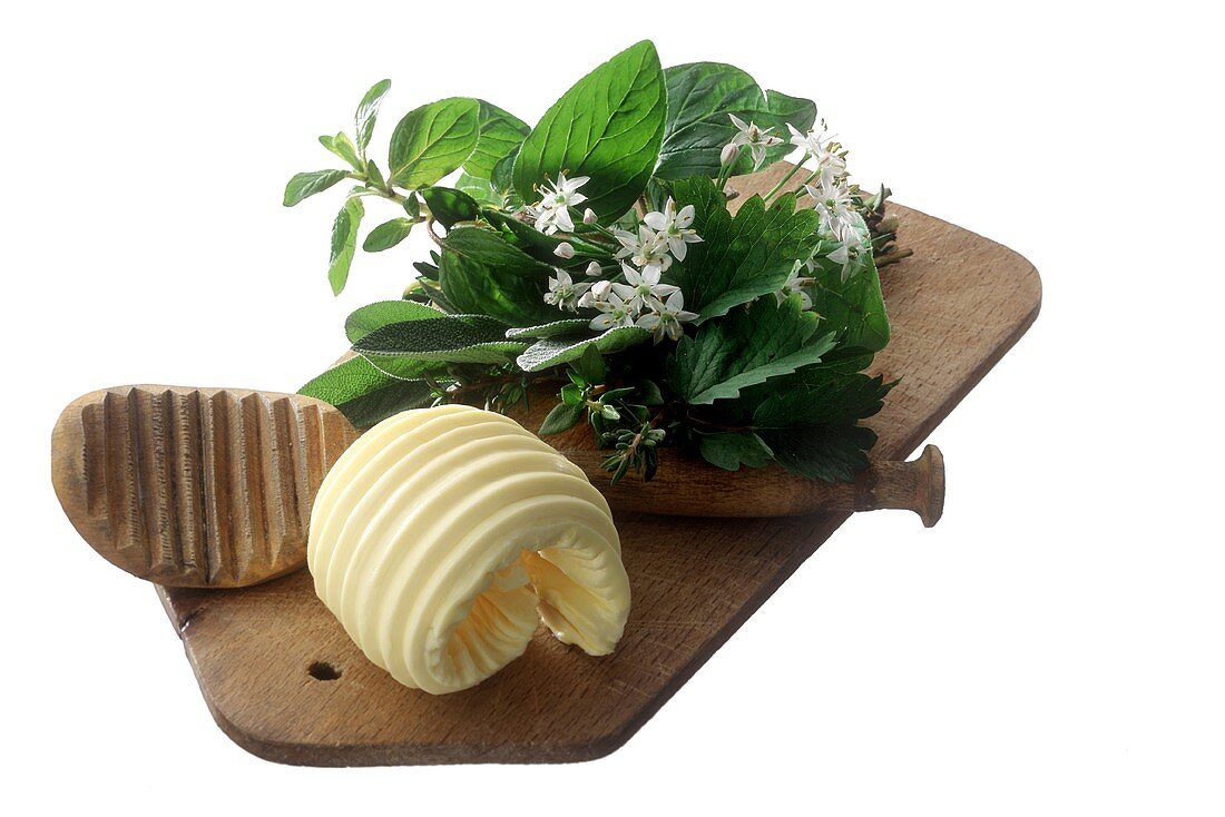 Butter curl on wooden board with herb bouquet