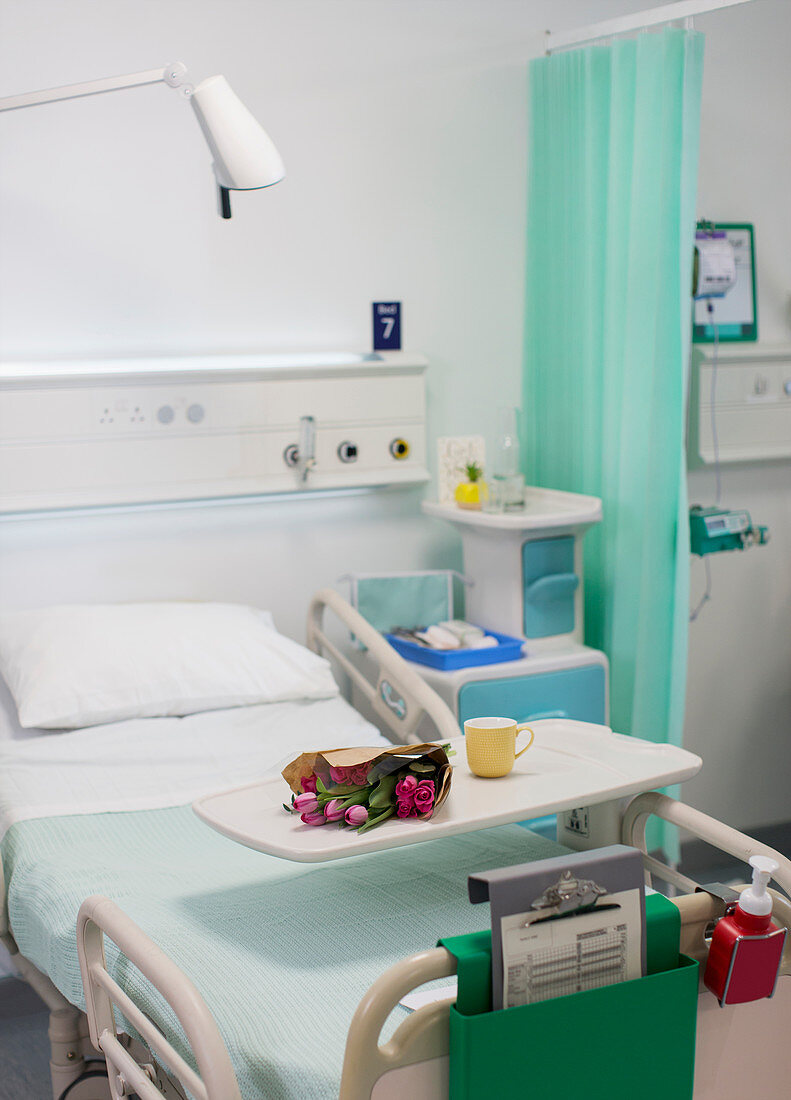 Flowers on tray over hospital bed in vacant hospital room