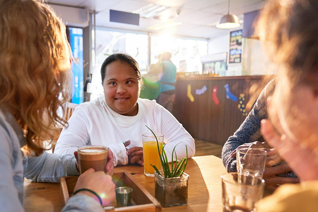 Woman with Down Syndrome talking with friends in cafe