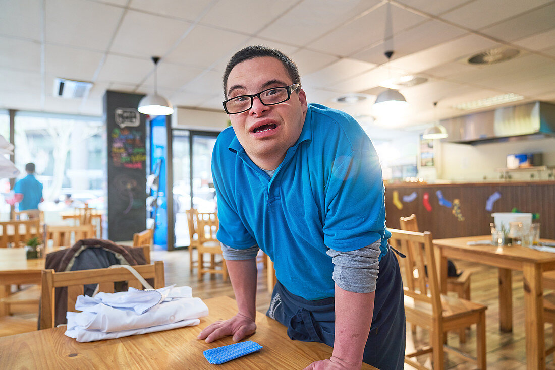 Portrait young man with Down Syndrome working in cafe