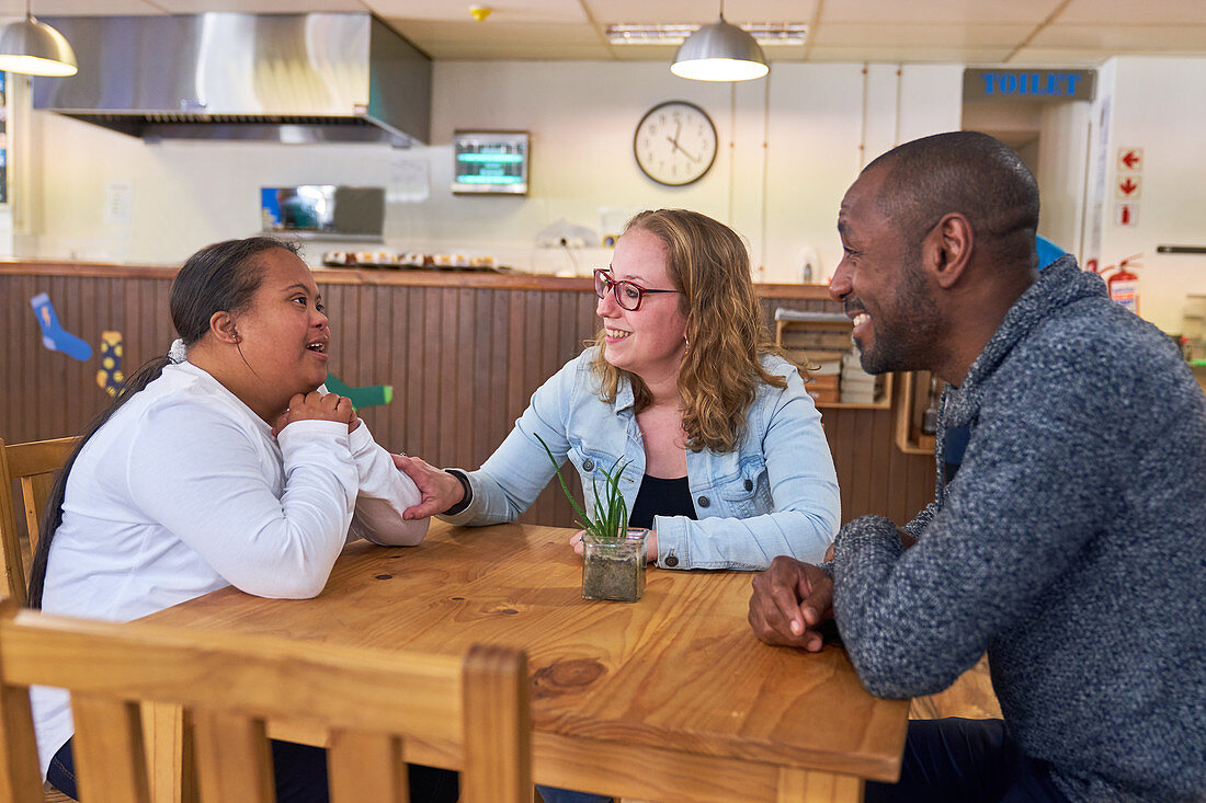 Parents and daughter with Down Syndrome talking in cafe