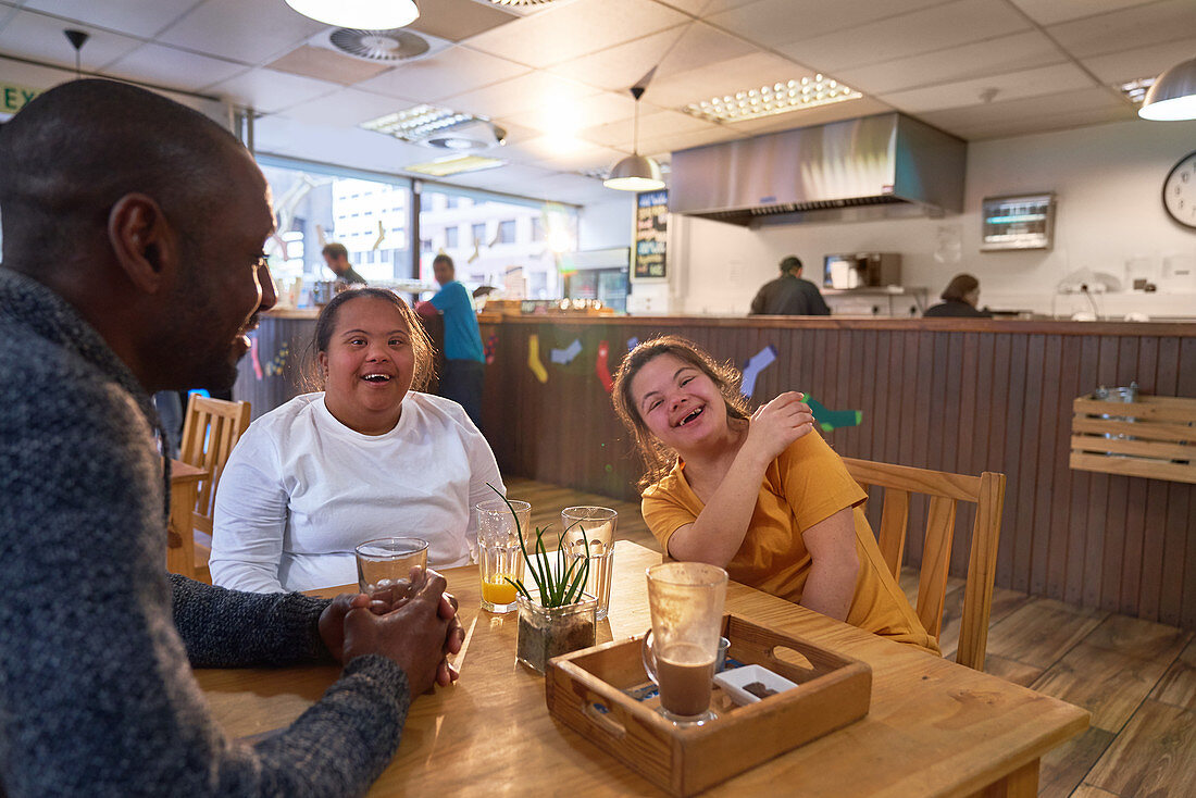 Happy women friends with Down Syndrome laughing in cafe